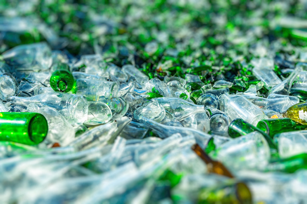 background of green and clear recycled glass bottles that's broken in a landfill